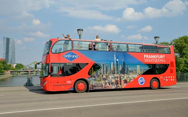 Frankfurt sightseeing bus on a bridge with skyline in the background.