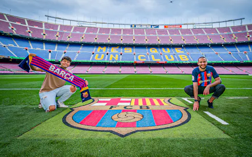 Fans at FC Barcelona's Camp Nou stadium with team scarf and emblem.
