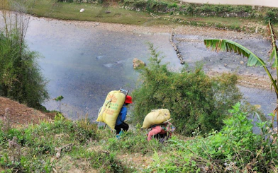 People carrying sacks along a riverbank in Mu Cang Chai, Vietnam.