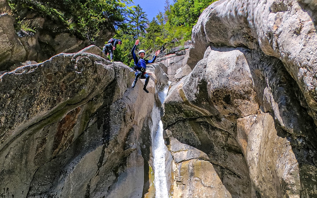 Person jumping off a rock into a canyon waterfall in Interlaken.