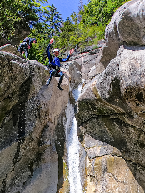 Person jumping off a rock into a canyon waterfall in Interlaken.