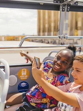 Children on a double-decker bus enjoying an audio-guided tour in Paris.