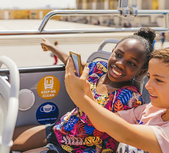 Children on a double-decker bus enjoying an audio-guided tour in Paris.