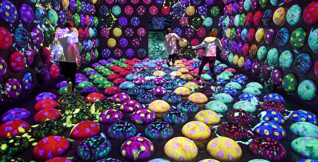 Visitors exploring colorful interactive exhibit at E・ZO FUKUOKA teamLab Forest.
