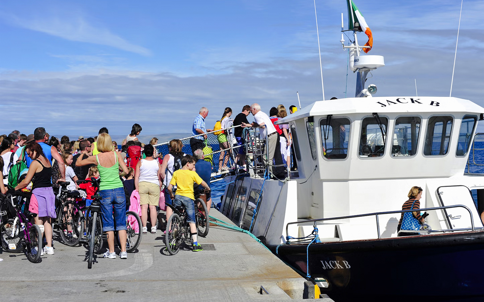 People boarding a ferry at Doolin Pier, Ireland, with bicycles nearby.