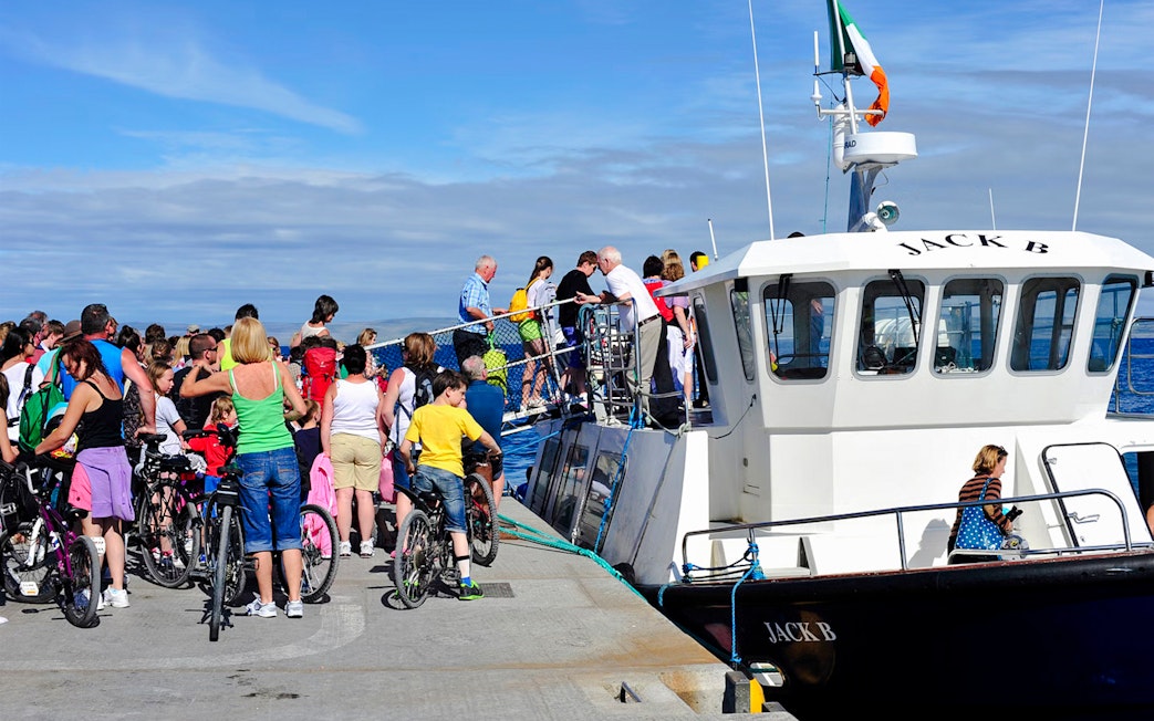 People boarding a ferry at Doolin Pier, Ireland, with bicycles nearby.