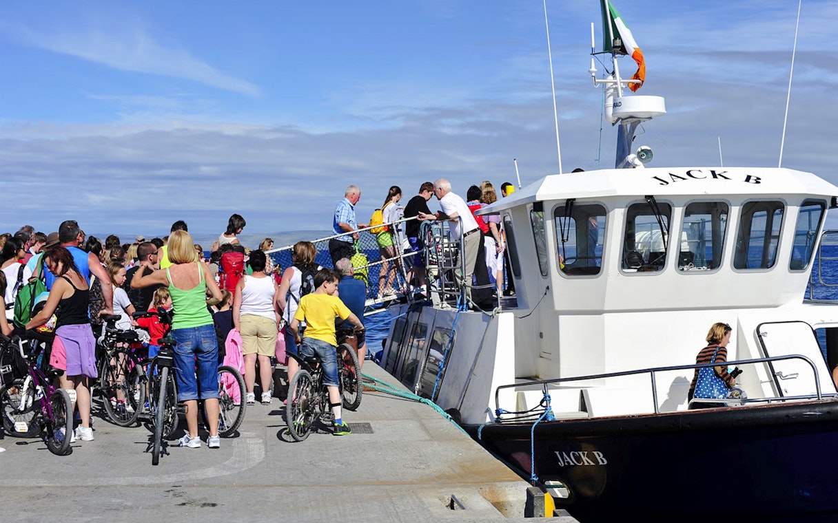 People boarding a ferry at Doolin Pier, Ireland, with bicycles nearby.