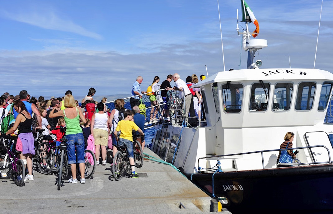 People boarding a ferry at Doolin Pier, Ireland, with bicycles nearby.