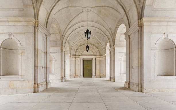Arched hallway inside Lisboa Story Centre with stone columns and lanterns.