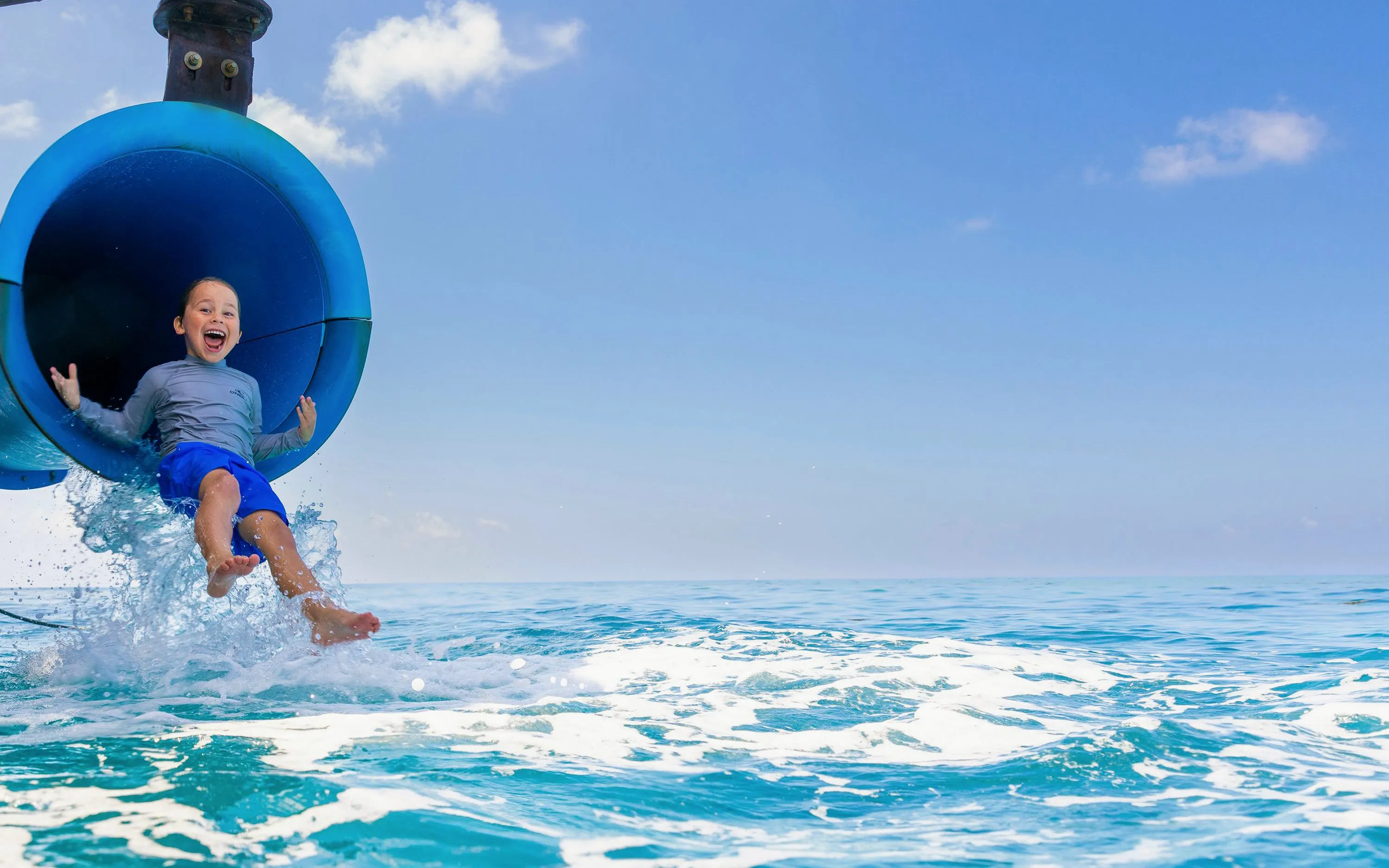 Child sliding into ocean from water slide on Sunlover Reef Cruises, Great Barrier Reef.