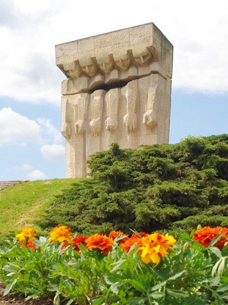 Monument to the Victims of Fascism Plaszow in Krakow with surrounding greenery and flowers.