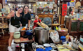 Visitors enjoying local cuisine at Amphawa Floating Market, Thailand, during a private shore excursion.