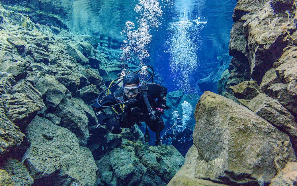 Snorkeler exploring Silfra Fissure's clear waters between tectonic plates in Iceland.