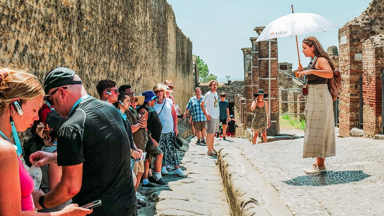 Tour guide leading a group at Pompeii ruins, Italy.