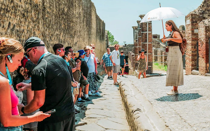 Tour guide leading a group at Pompeii ruins, Italy.