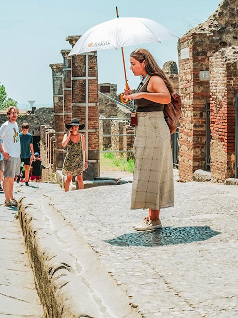 Tour guide leading a group at Pompeii ruins, Italy.