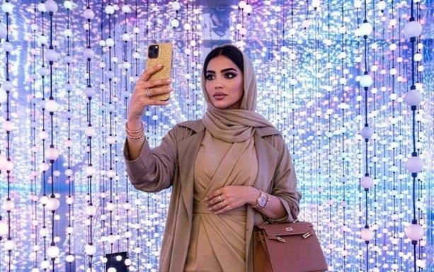 Woman taking a selfie at Dopamine Land, Dubai with colorful light display.