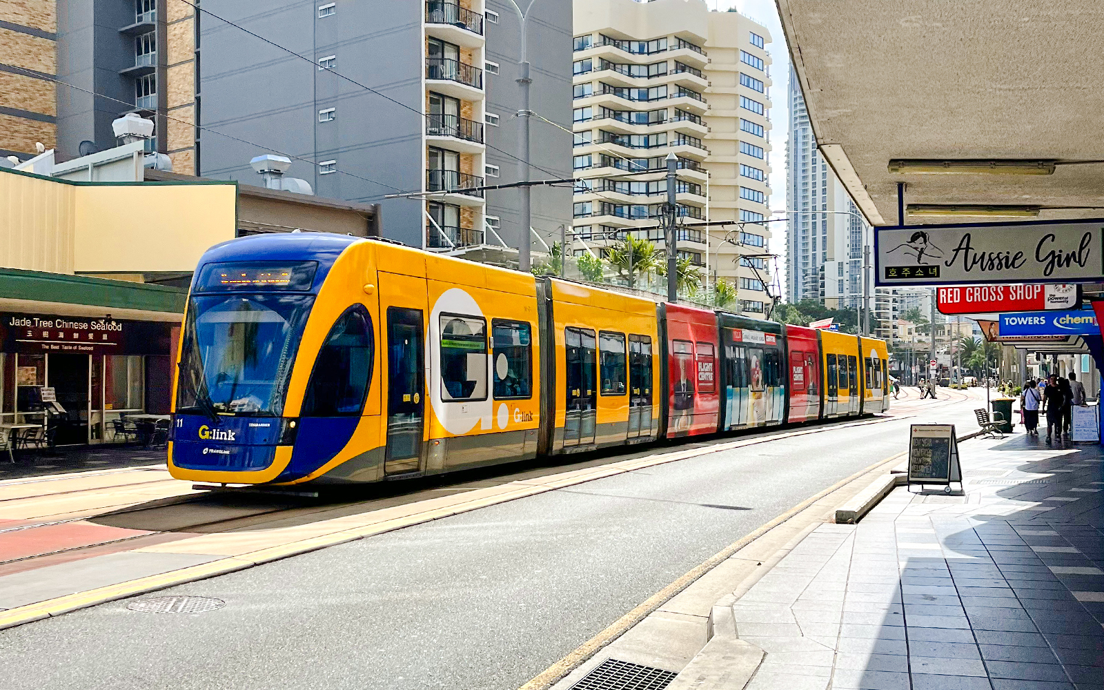 Tram on Gold Coast street with high-rise buildings in the background.