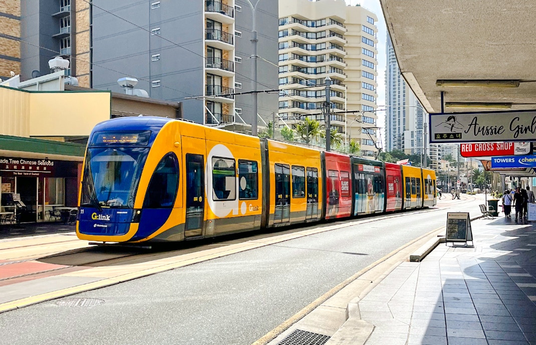 Tram on Gold Coast street with high-rise buildings in the background.