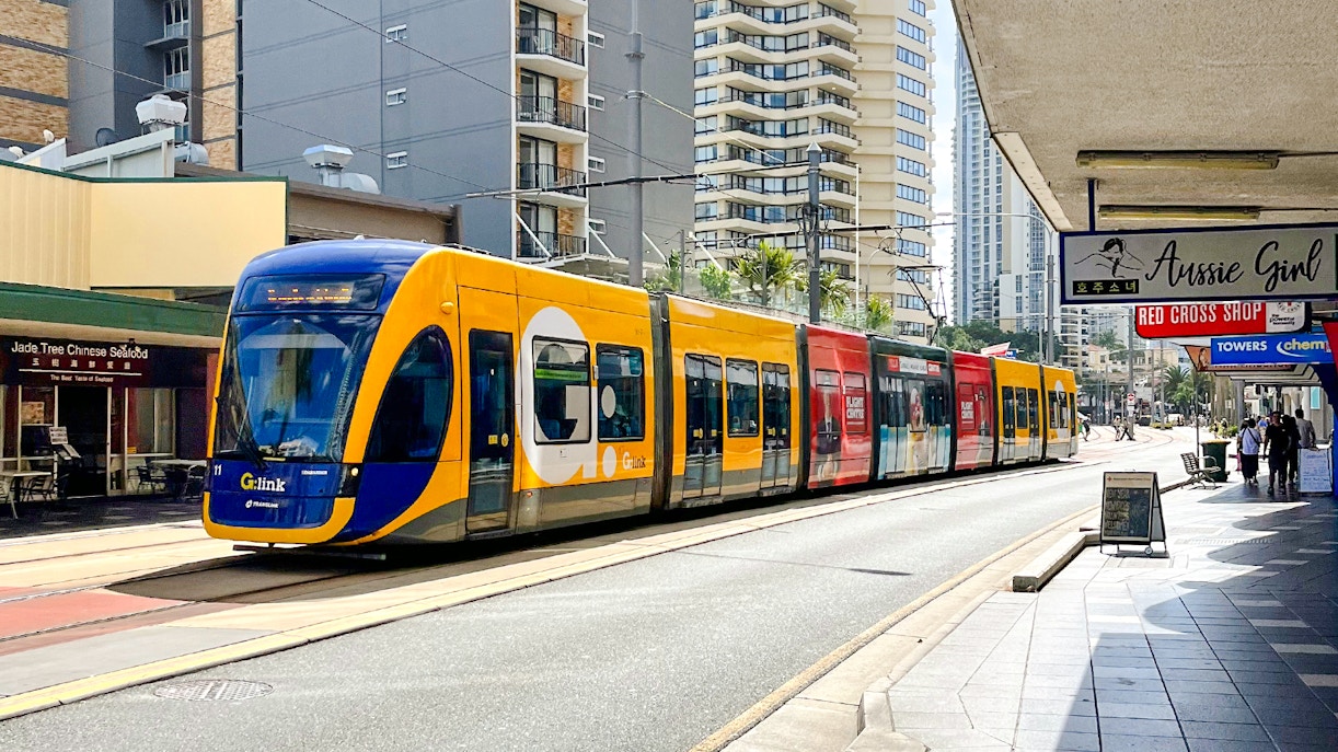 Tram on Gold Coast street with high-rise buildings in the background.