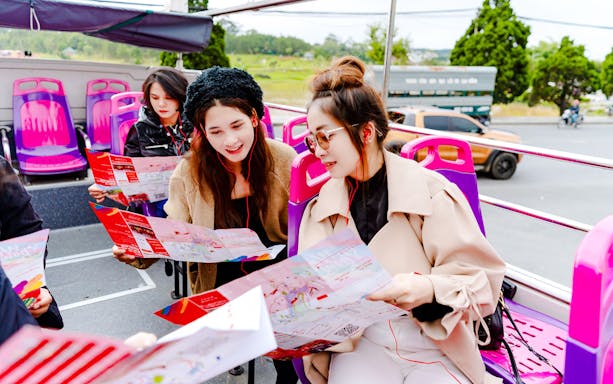 Visitors reading maps on Hop on Hop off bus upper deck in Da Lat.