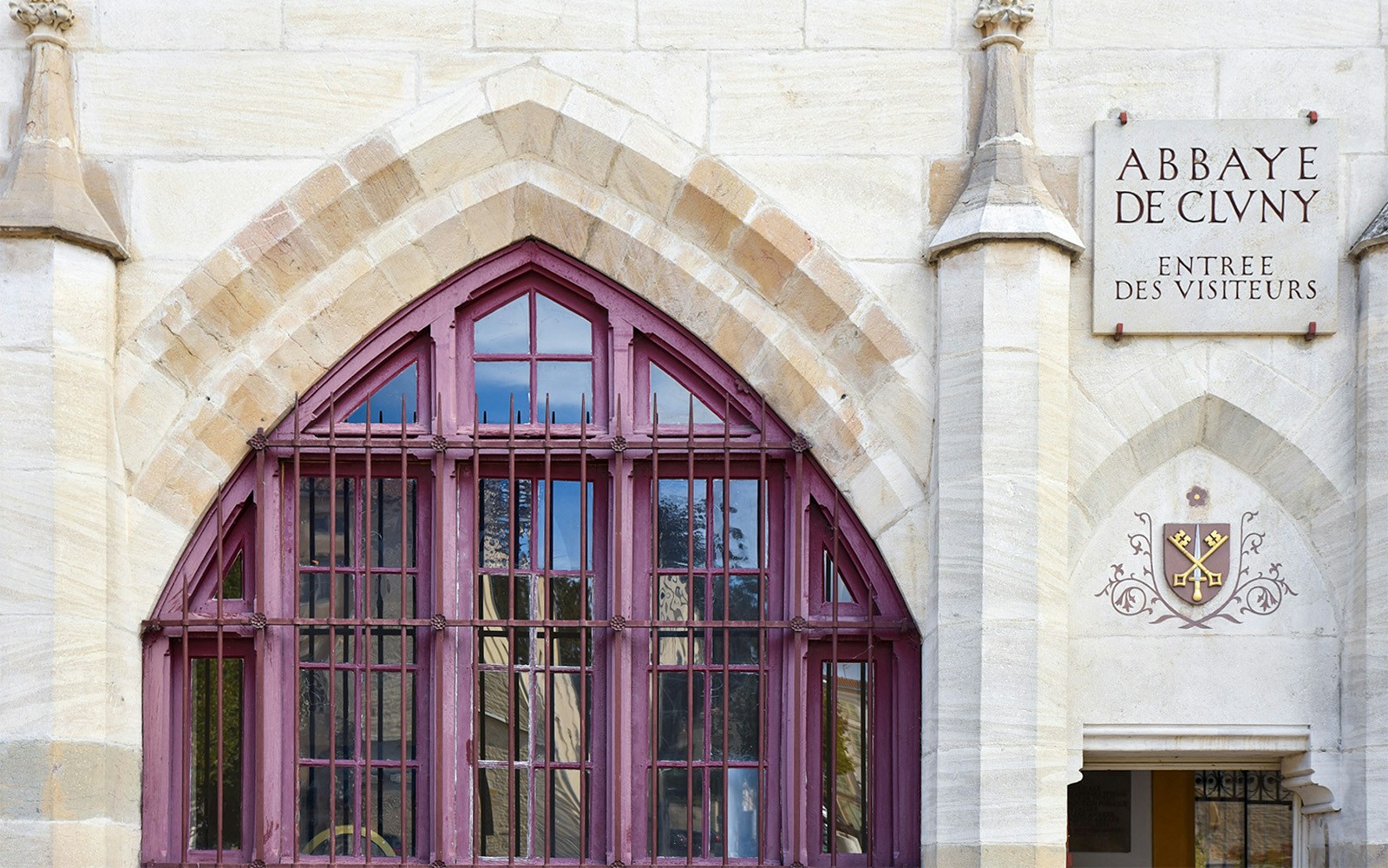 Cluny Abbey entrance with arched window and visitor sign.