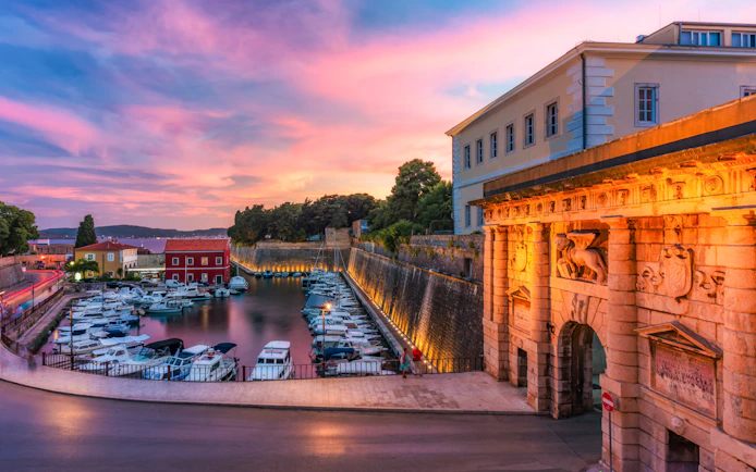 Land Gate in Zadar at sunset with boats docked in the harbor, Croatia.