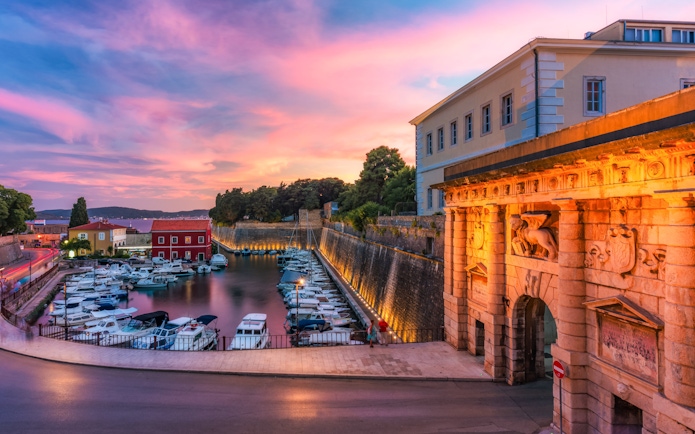 Land Gate in Zadar at sunset with boats docked in the harbor, Croatia.