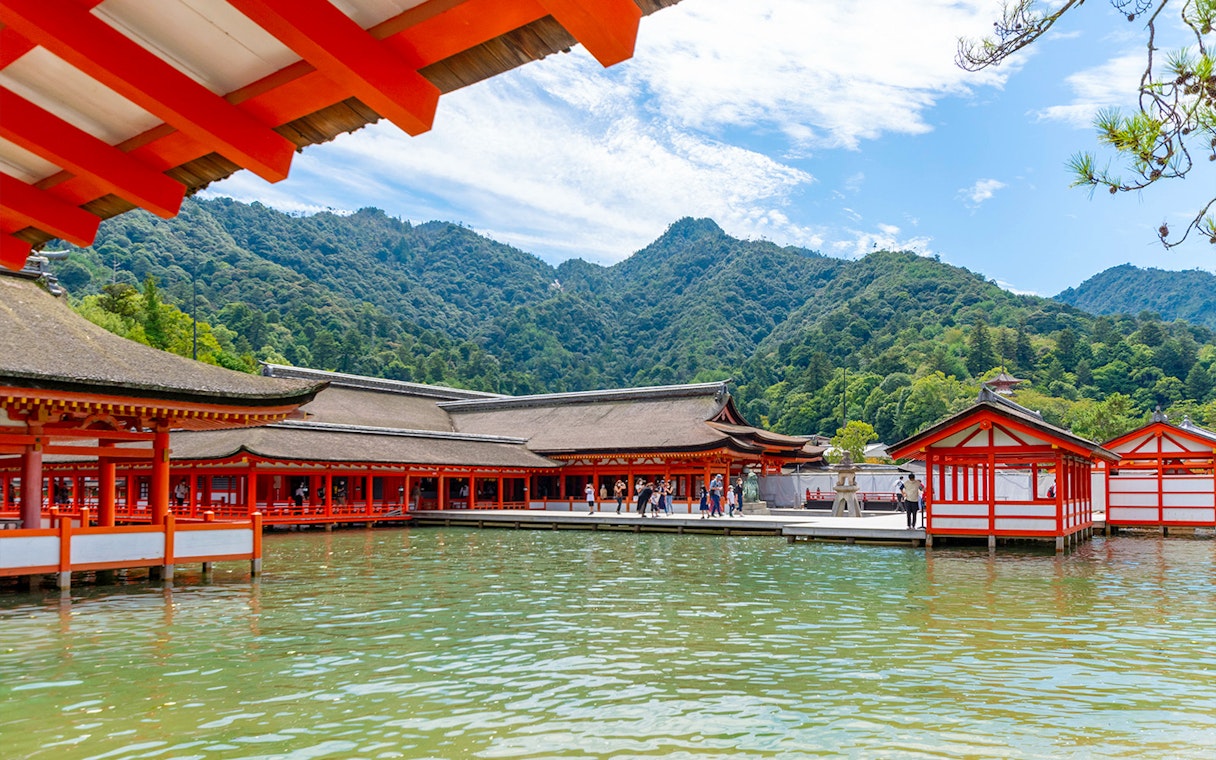 Itsukushima Shrine on Miyajima Island with mountains in the background, part of Hiroshima and Miyajima 1 Day Bus Tour.