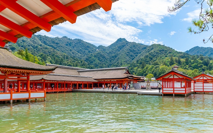 Itsukushima Shrine on Miyajima Island with mountains in the background, part of Hiroshima and Miyajima 1 Day Bus Tour.