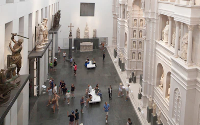 Sculpture Gallery at Opera del Duomo Museum in Florence with visitors exploring exhibits.