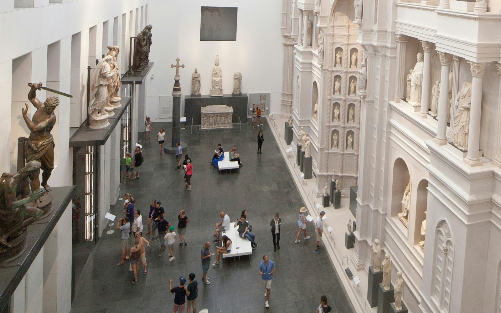 Sculpture Gallery at Opera del Duomo Museum, Florence, with visitors exploring statues.