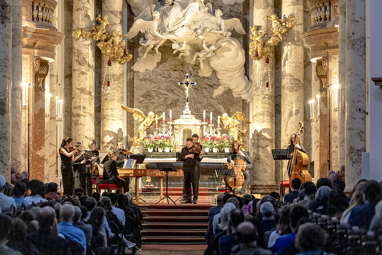 Musicians performing Vivaldi's Four Seasons in an ornate concert hall.