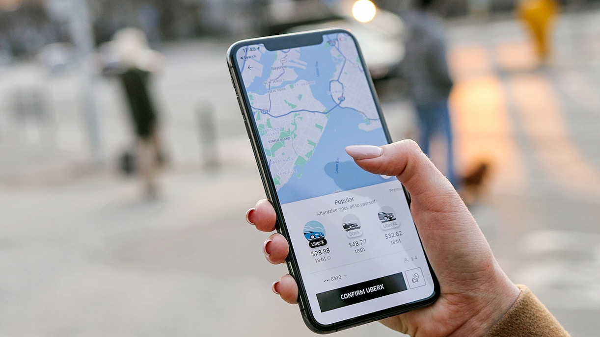 Hand holding phone displaying Uber app with map and ride options.
