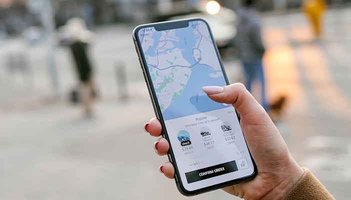 Hand holding phone displaying Uber app with map and ride options.