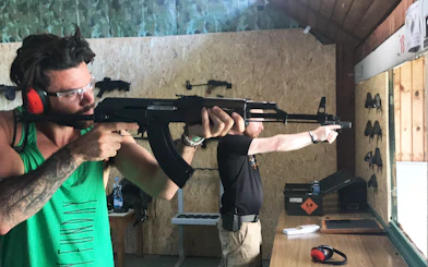 Participants aiming rifles at an indoor shooting range.