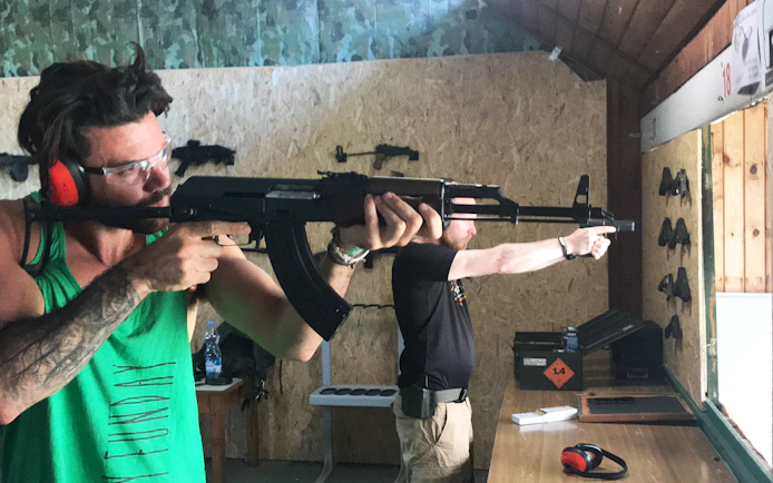 Participants aiming rifles at an indoor shooting range.