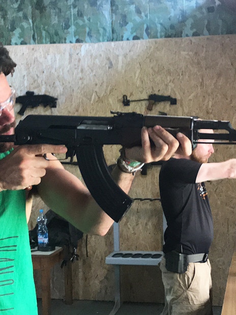 Participants aiming rifles at an indoor shooting range.