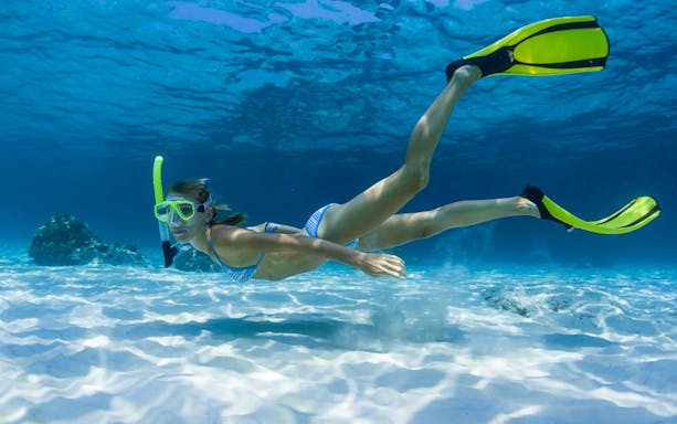 Snorkeler exploring underwater coves along the coastline.