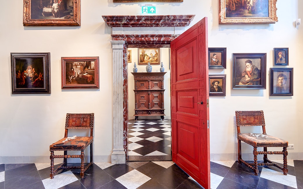Rembrandt House Museum interior with paintings, red door, and antique furniture.