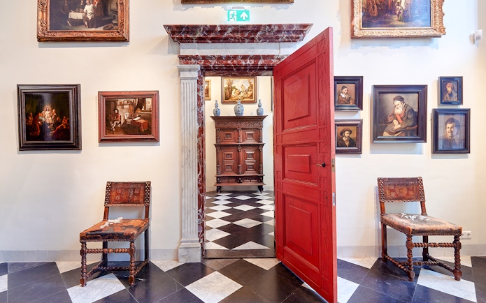 Rembrandt House Museum interior with paintings, red door, and antique furniture.