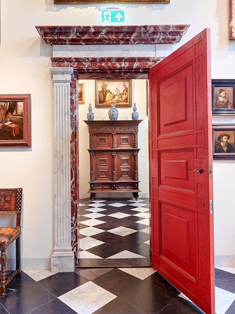 Rembrandt House Museum interior with paintings, red door, and antique furniture.