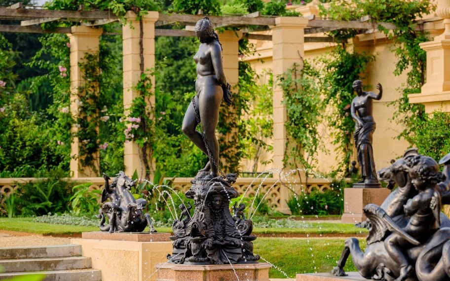 Terrace garden with ornate statues and water fountains surrounded by lush greenery.