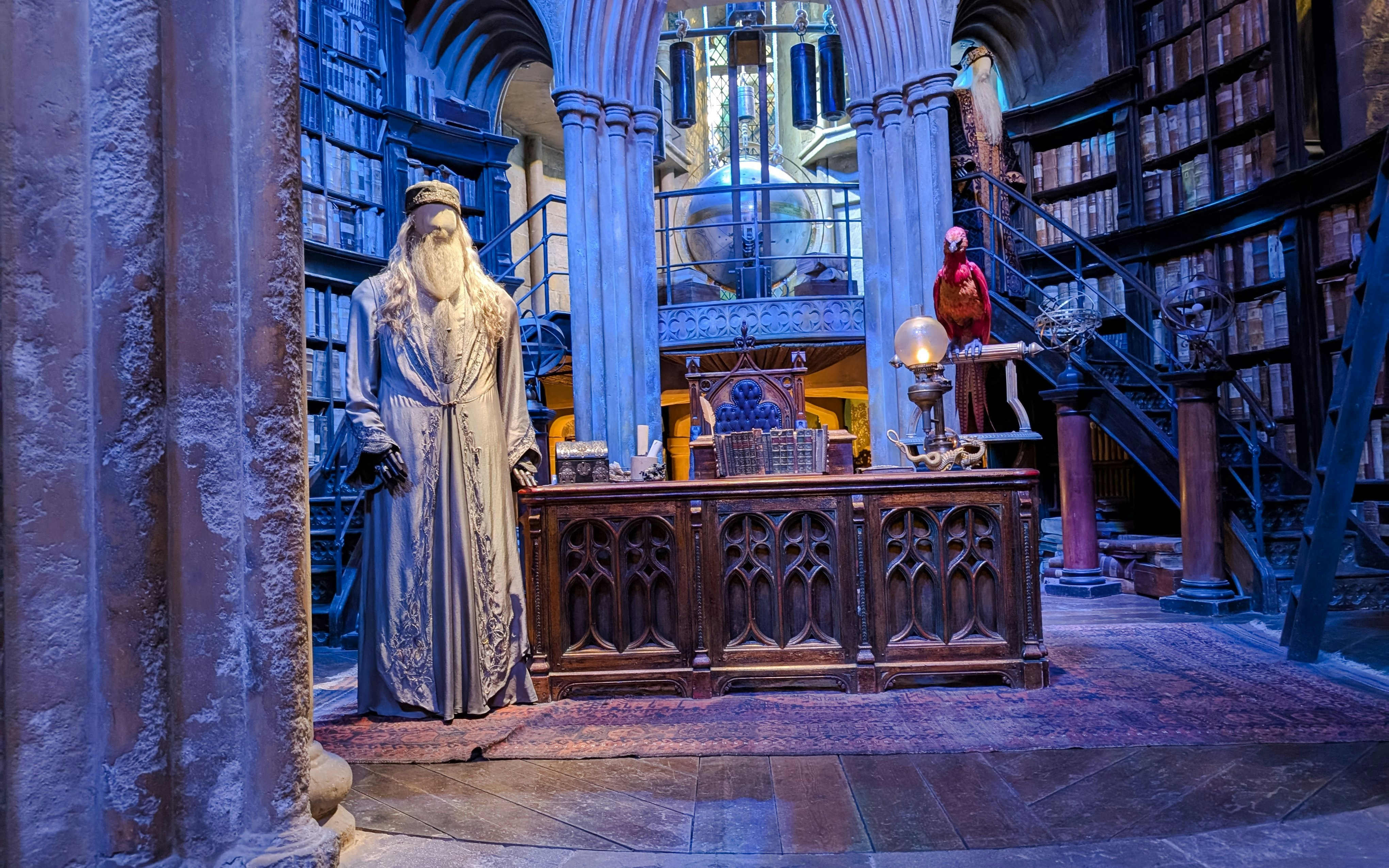 Professor Dumbledore’s office with bookshelves, desk, and phoenix statue.
