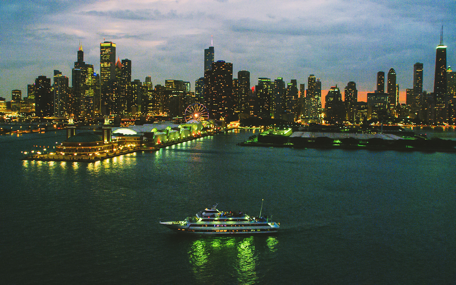 Cruise ship sailing on Lake Michigan with Chicago skyline at dusk.