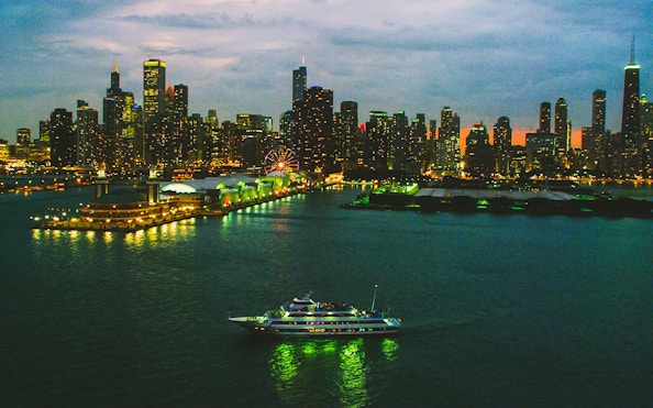 Cruise ship sailing on Lake Michigan with Chicago skyline at dusk.
