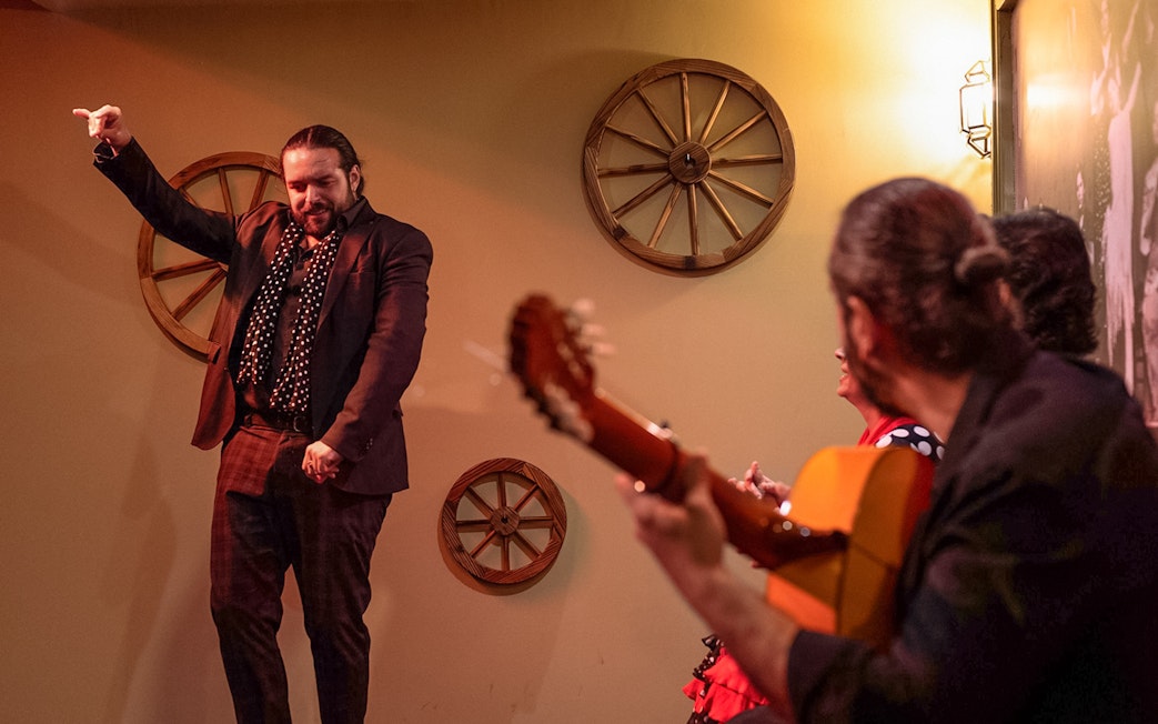 Flamenco dancer performing at Tablao La Cantaora in Seville with guitarist in foreground.