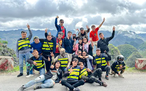 Group of tourists on Ha Giang Loop motorbike tour with scenic mountain backdrop.