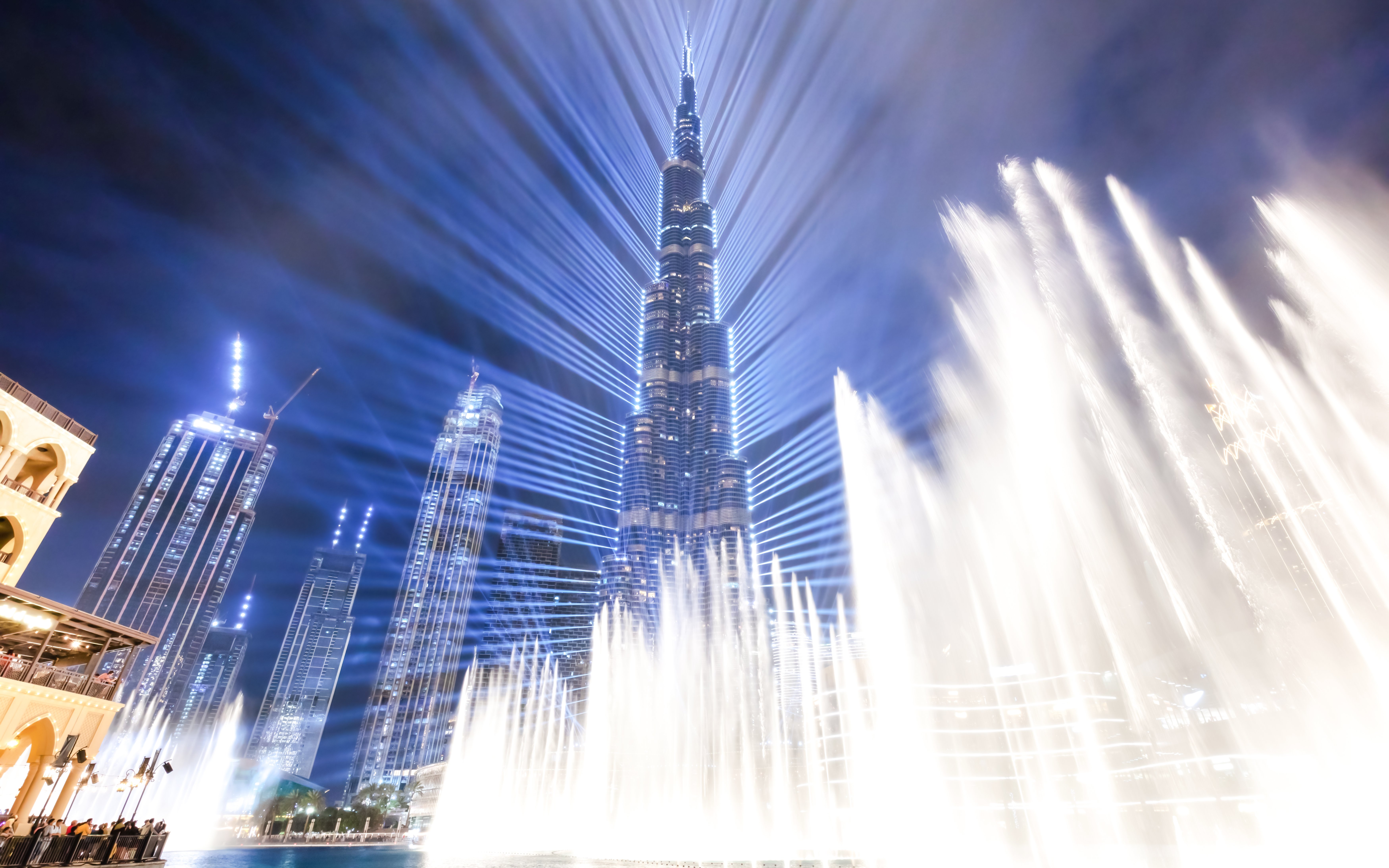 Dubai Fountain show with Burj Khalifa illuminated at night.
