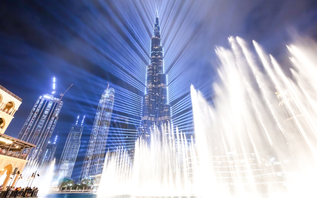 Dubai Fountain show with Burj Khalifa illuminated at night.